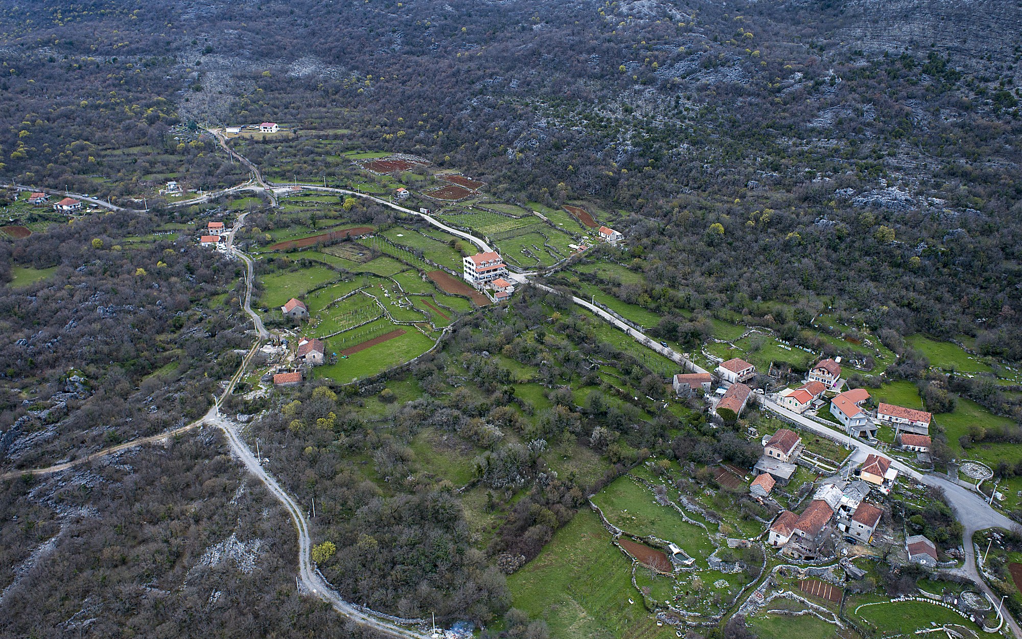 Selo, crkvica uz groblje i njive ograđene suvomeđama, iz vazduha